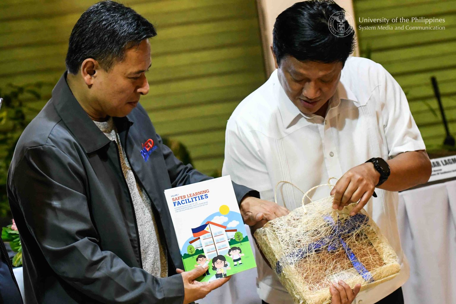 DepEd Secretary Juan Edgardo “Sonny” Angara (left) hands UP President Angelo Jimenez a copy of Pillar 1: Safer Learning Facilities Guidebook, a manual that offers practical advice on adopting “inclusive, climate-resilient, and child-safe construction standards.” The safety guidebook was launched October 2025 in collaboration with the UN Children’s Fund and Good Neighbors International Philippines. Photo by Kevin Roque, UPS-MCO.